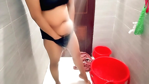 Indian housewife showering with water in her bedroom